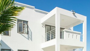A modern two-story house with a swimming pool, large windows, and a balcony. - 4 Bedroom Private Villa Villa La Tourelle (Tamarin)