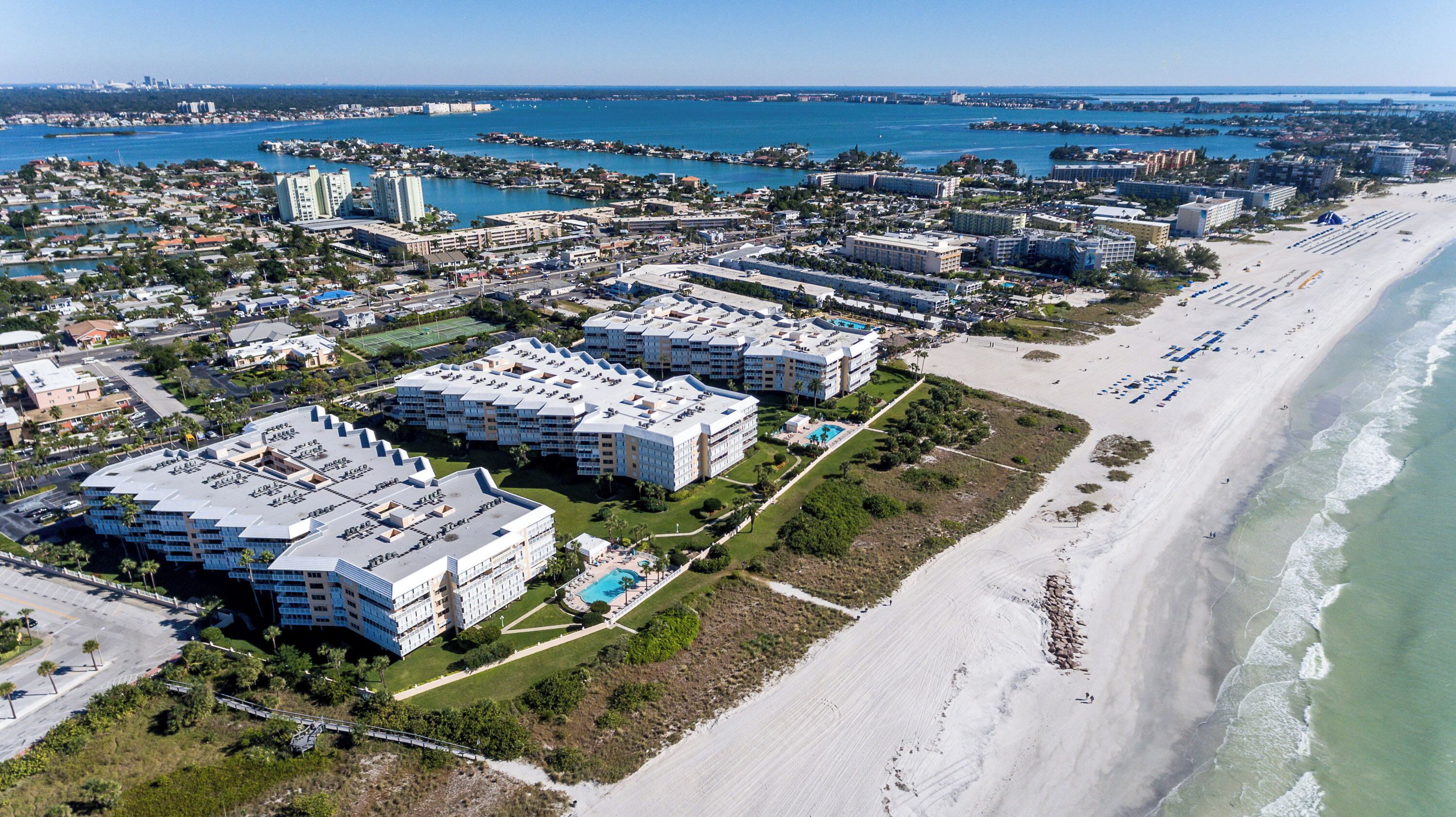 Vista aérea de una zona hotelera costera con varios edificios, una playa y un puerto deportivo.