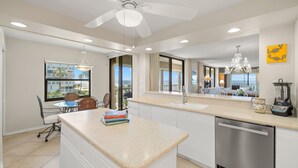 A modern kitchen with a central island, a dishwasher, and a view of the ocean.