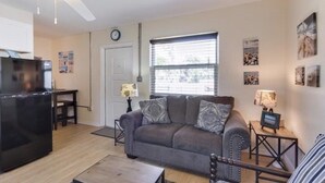 A living room with a gray sofa, a coffee table, a TV, and a ceiling fan.