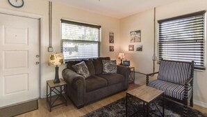 A living room with a dark brown sofa, a striped armchair, a coffee table, and a ceiling fan.