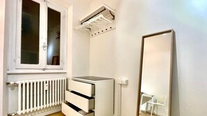 A small, bright room with a window, a radiator, a white wardrobe, a mirror, and a chair. - Elegante Appartamento Vista sul Duomo di Firenze  (Firenze)