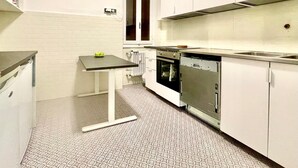 A compact kitchen with white cabinets, a small table with apples, a built-in oven, and a dishwasher. - Elegante Appartamento Vista sul Duomo di Firenze  (Firenze)