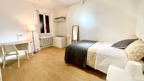 A bedroom with a bed, a desk, a chair, a radiator, and a window. - Elegante Appartamento Vista sul Duomo di Firenze  (Firenze)