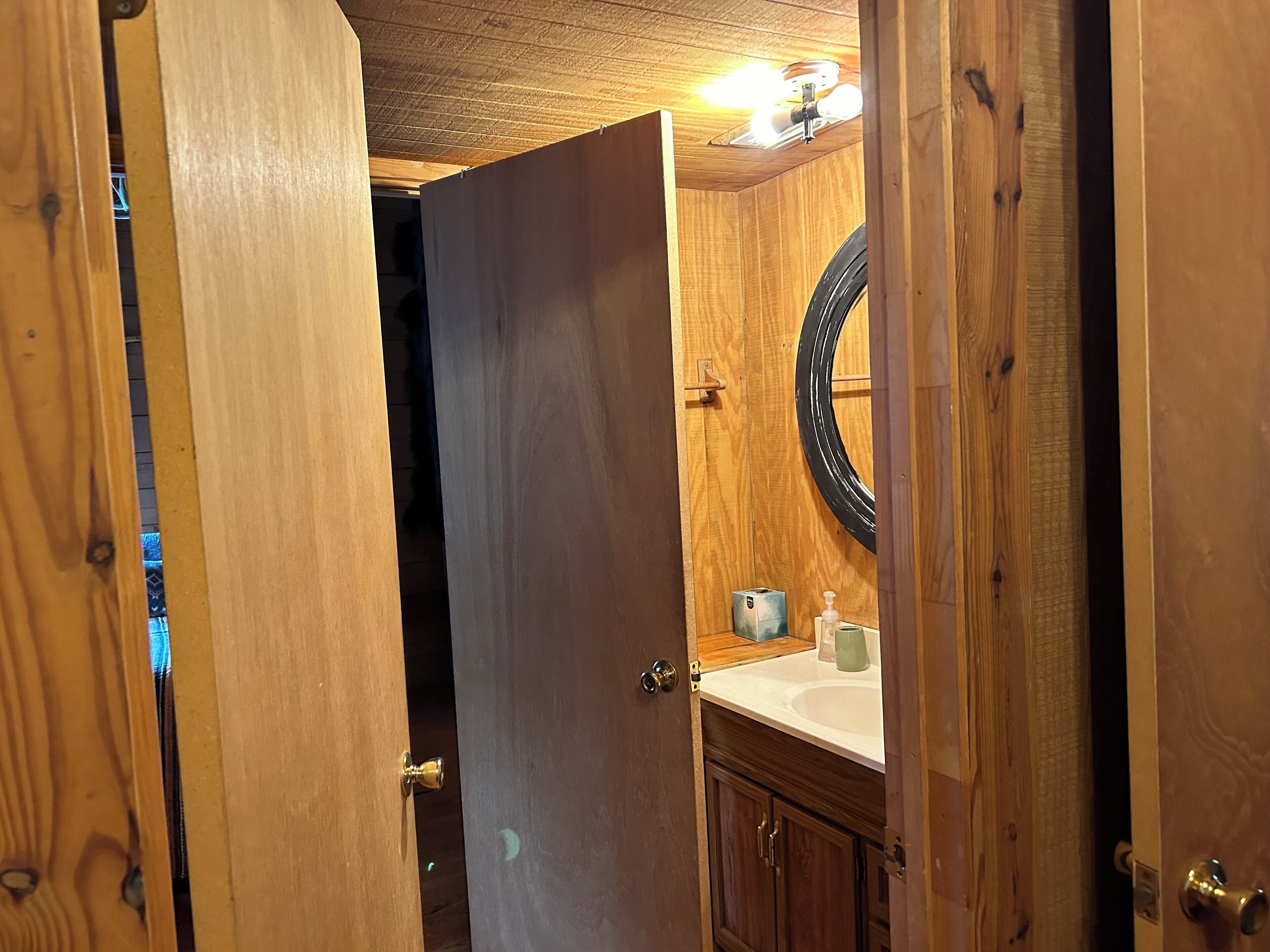 A wooden bathroom with a sink, mirror, and cabinet.