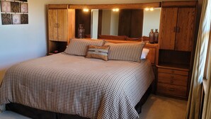 Une chambre à coucher avec un grand lit, une armoire en bois et un miroir au-dessus du lit.