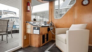 Un intérieur chaleureux avec un coin bar en bois, un canapé en cuir blanc et une grande fenêtre.