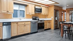 Une cuisine moderne avec des armoires en bois, des appareils électroménagers en acier inoxydable et une grande fenêtre.