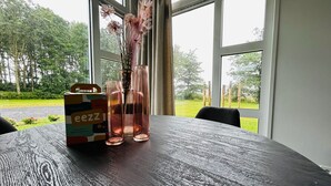 Une table avec un plateau en bois, un vase en verre contenant des fleurs séchées et une pancarte « Bienvenue ».