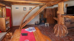 Ein gemütliches Wohnzimmer mit Holzboden, Kamin, Fernseher und einem roten Teppich.