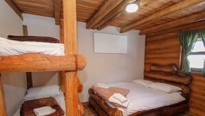 A wooden bunk bed room with a single bed and a small table.