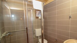 A bathroom with a glass-enclosed shower, a toilet, and a sink.