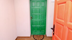 Une porte verte avec une poignée en métal et un paillasson devant.