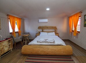 A bedroom with a wooden bed, a desk, a chair, and a small table.