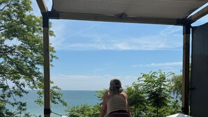 A person sitting on a hammock under a shaded area with a view of the sea. - Artisan's Cove at Water's Edge by Liberty with Golf Simulator (Municipality Of Chatham-Kent)