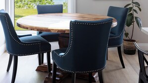 A dining area with a round wooden table, four upholstered chairs, a hanging pendant light, and a colorful abstract painting on the wall. - Artisan's Cove at Water's Edge by Liberty with Golf Simulator (Municipality Of Chatham-Kent)