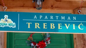 Un cartello con la scritta 'APARTMAN TREBEVIĆ' e un logo raffigurante un cervo e il testo 'OLINA MIRA'.