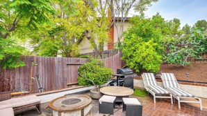 Un jardin avec un barbecue, des chaises longues et un foyer en pierre.