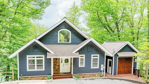 Ein zweistöckiges Haus mit Satteldach, einer Veranda und einer Garage.
