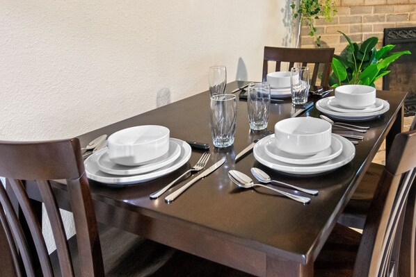 A dining table set with white plates, bowls, cutlery, and glasses.