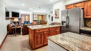 A modern kitchen with granite countertops, wooden cabinets, and a stainless steel refrigerator. - Ski In, Ski Out 1 Bedroom at the Eagle Bahn Gondola in Lionshead (Vail)