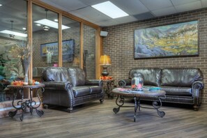 A lobby with two leather sofas, a round coffee table, and a painting on the wall.