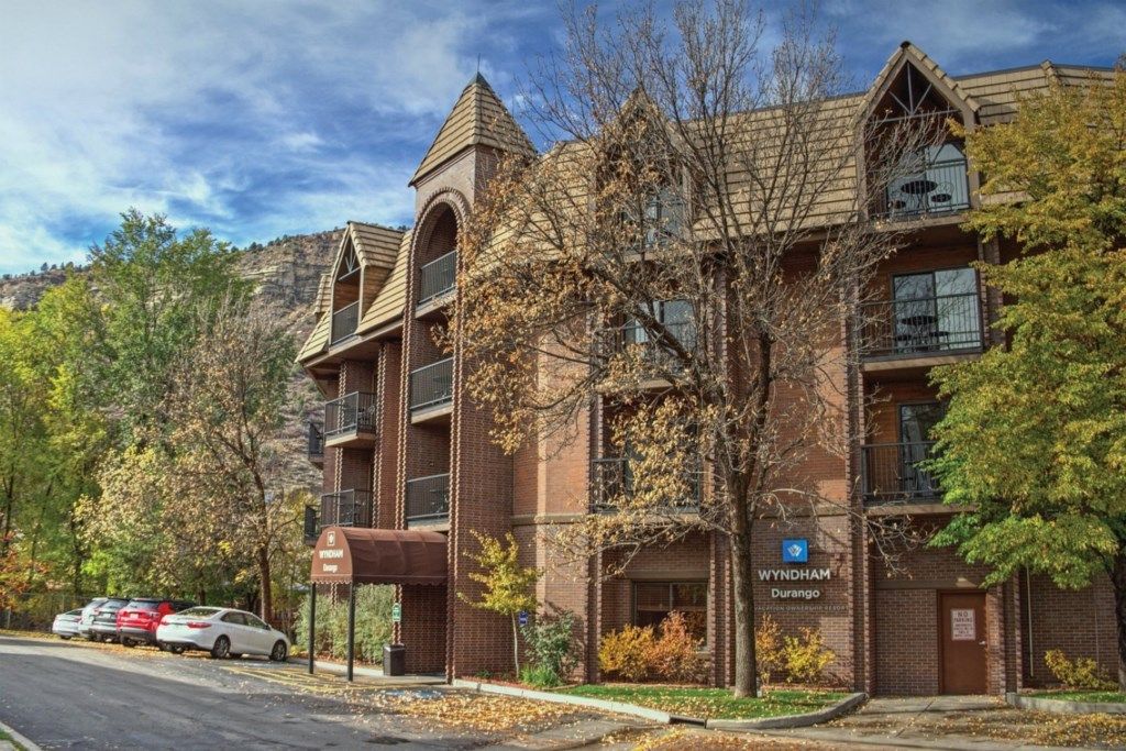 Un immeuble à plusieurs étages avec une façade en briques, une enseigne indiquant « Wyndham Durango » et un parking avec des voitures.