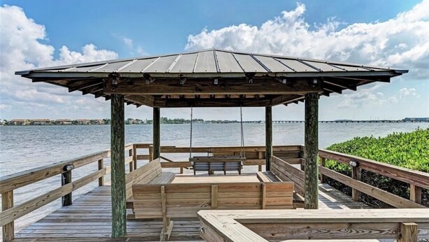 Un molo di legno con un gazebo, panchine e un'altalena.