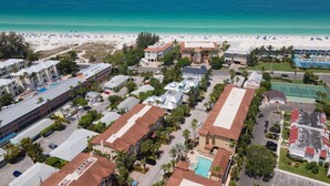 Vista aerea di un resort costiero con diversi edifici, una spiaggia e una limpida visuale sull'oceano.