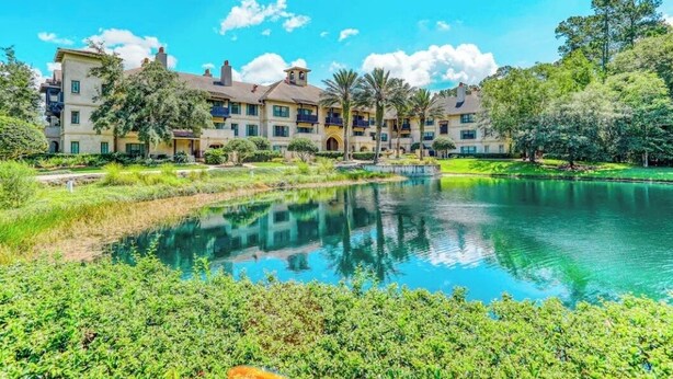 A hotel with a large outdoor pool surrounded by lush greenery and palm trees.
