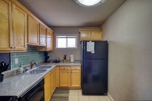 A compact kitchen with wooden cabinets, a black refrigerator, and a window. - Walk to Sanford Stadium/DT w/view Dawg Friendly! (Athens)