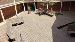Una terraza al aire libre con bancos de madera y un pequeño árbol.