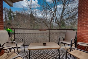 An outdoor patio area with a table and four chairs, a sign indicating a patio bar, and a view of trees and sky. - Walk to Sanford Stadium/DT w/view Dawg Friendly! (Athens)