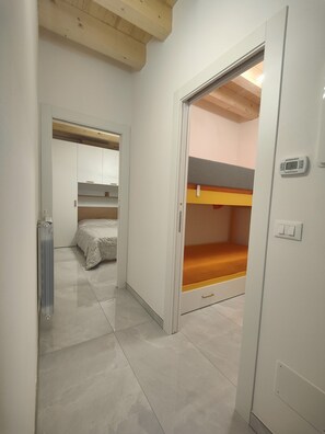 Cozy room with a bunk bed and single bed, featuring a tiled floor and digital thermostat.