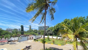 A residential area with a paved driveway, parked cars, and palm trees. - Jim Holiday Homes (Mombasa)