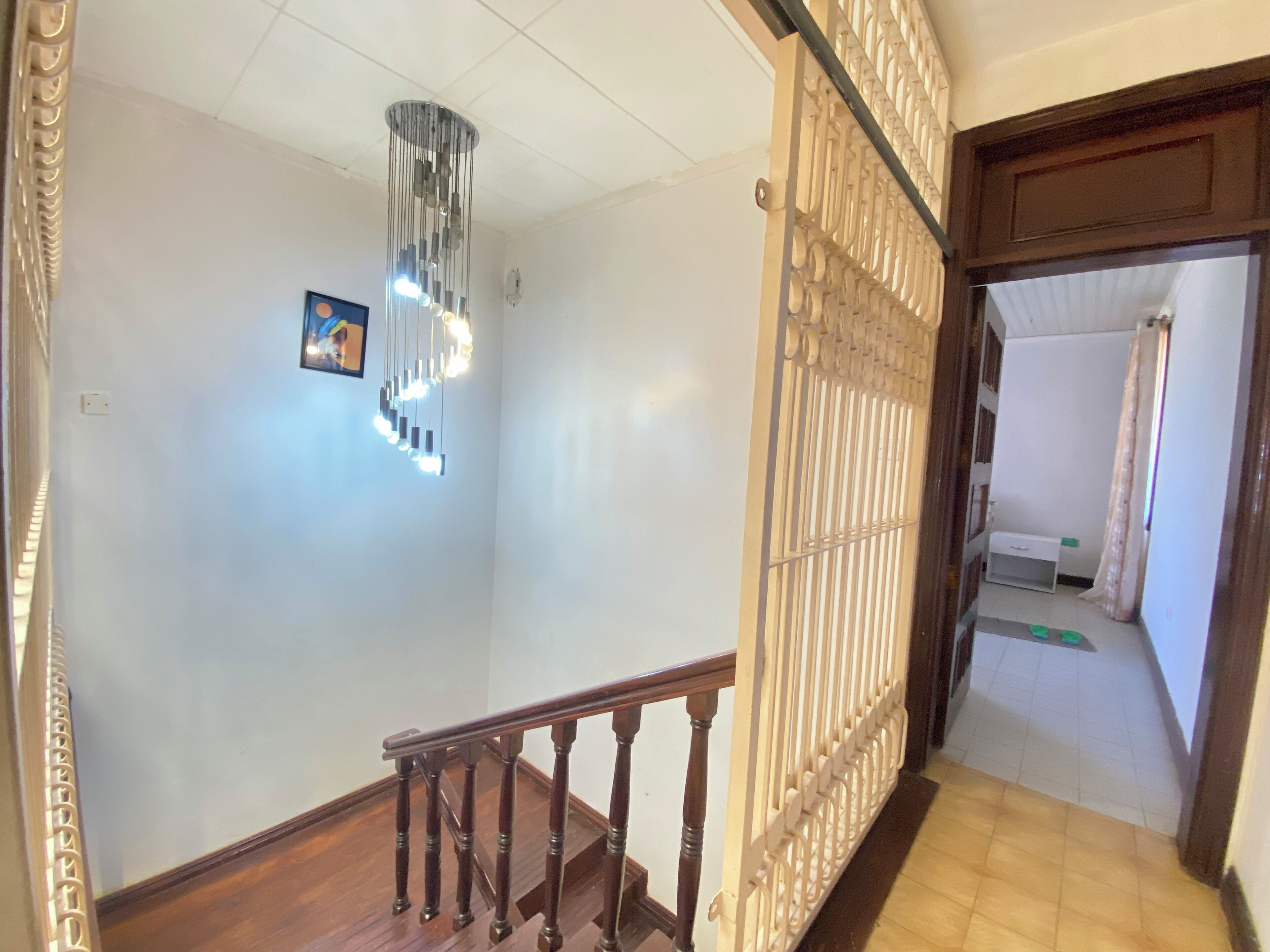 Un escalier avec une rampe en bois et un luminaire décoratif placé au-dessus.