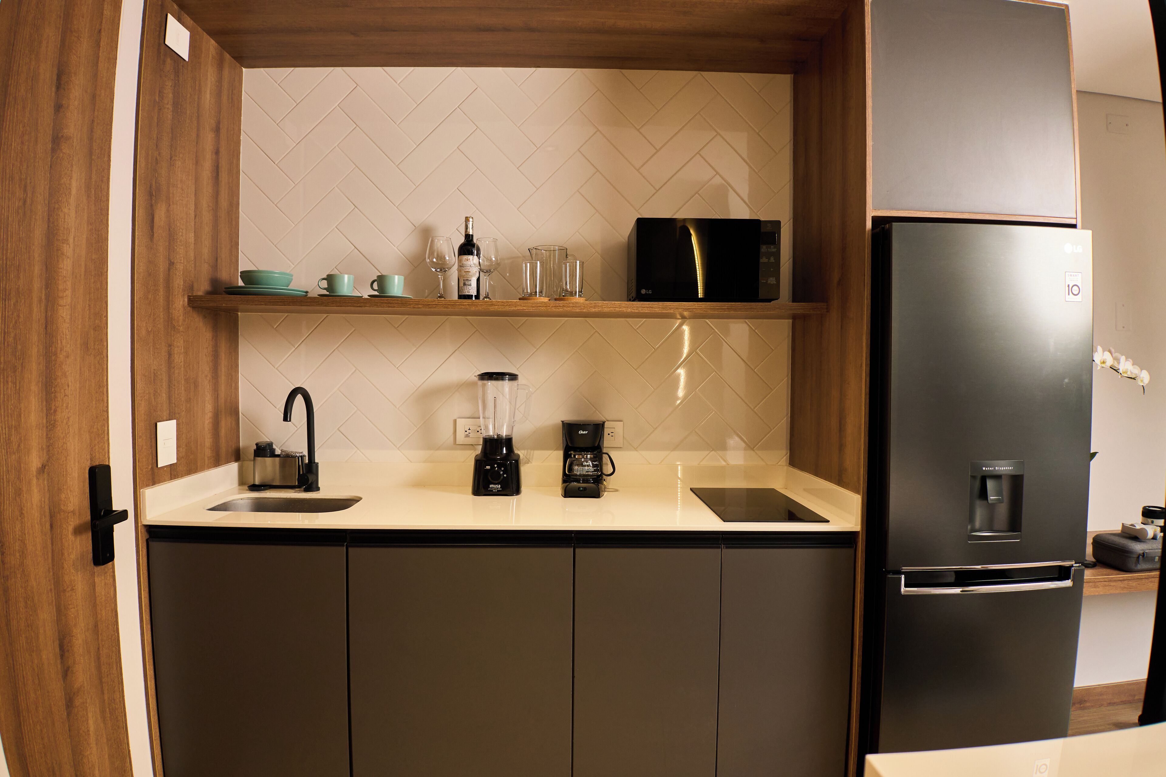 A modern kitchen with a black refrigerator, a coffee maker, and a blender on the counter.
