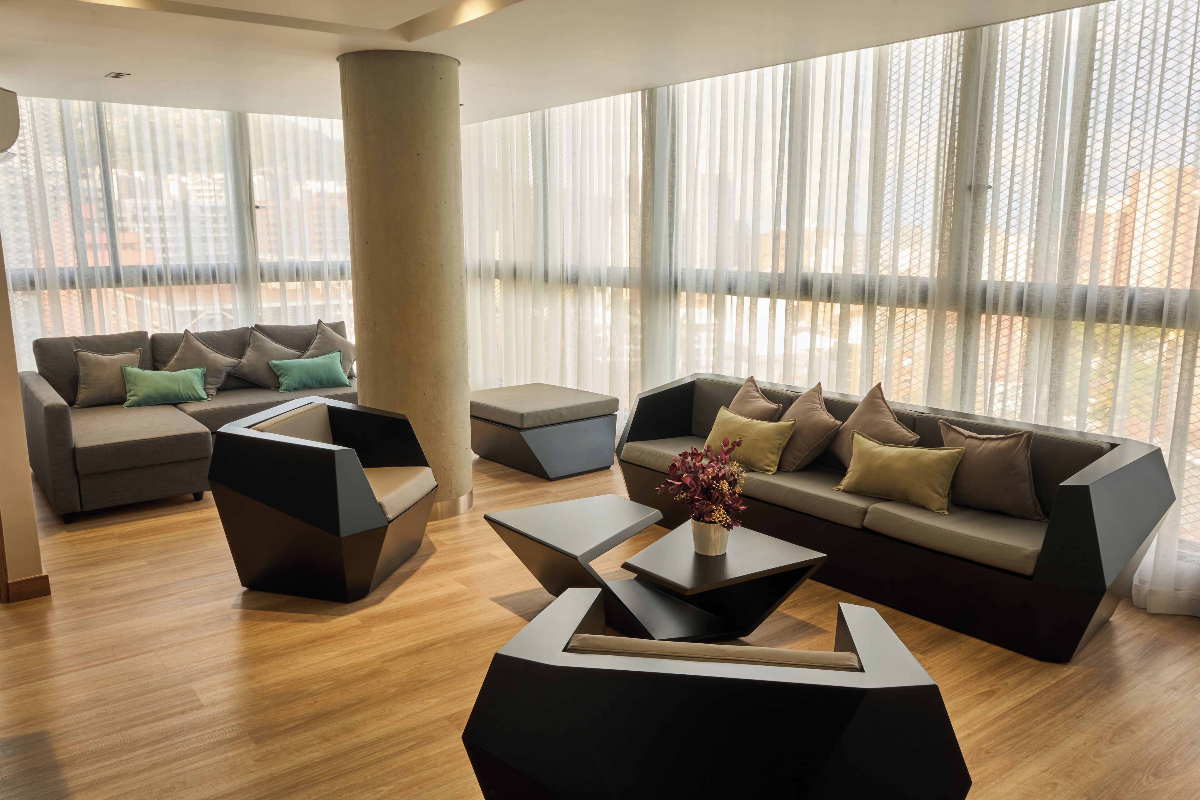 Una sala moderna con un sofá seccional, dos sillones y una mesa de centro.