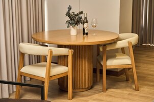 Una mesa redonda de madera con dos sillas, una planta en maceta, una botella y un vaso.