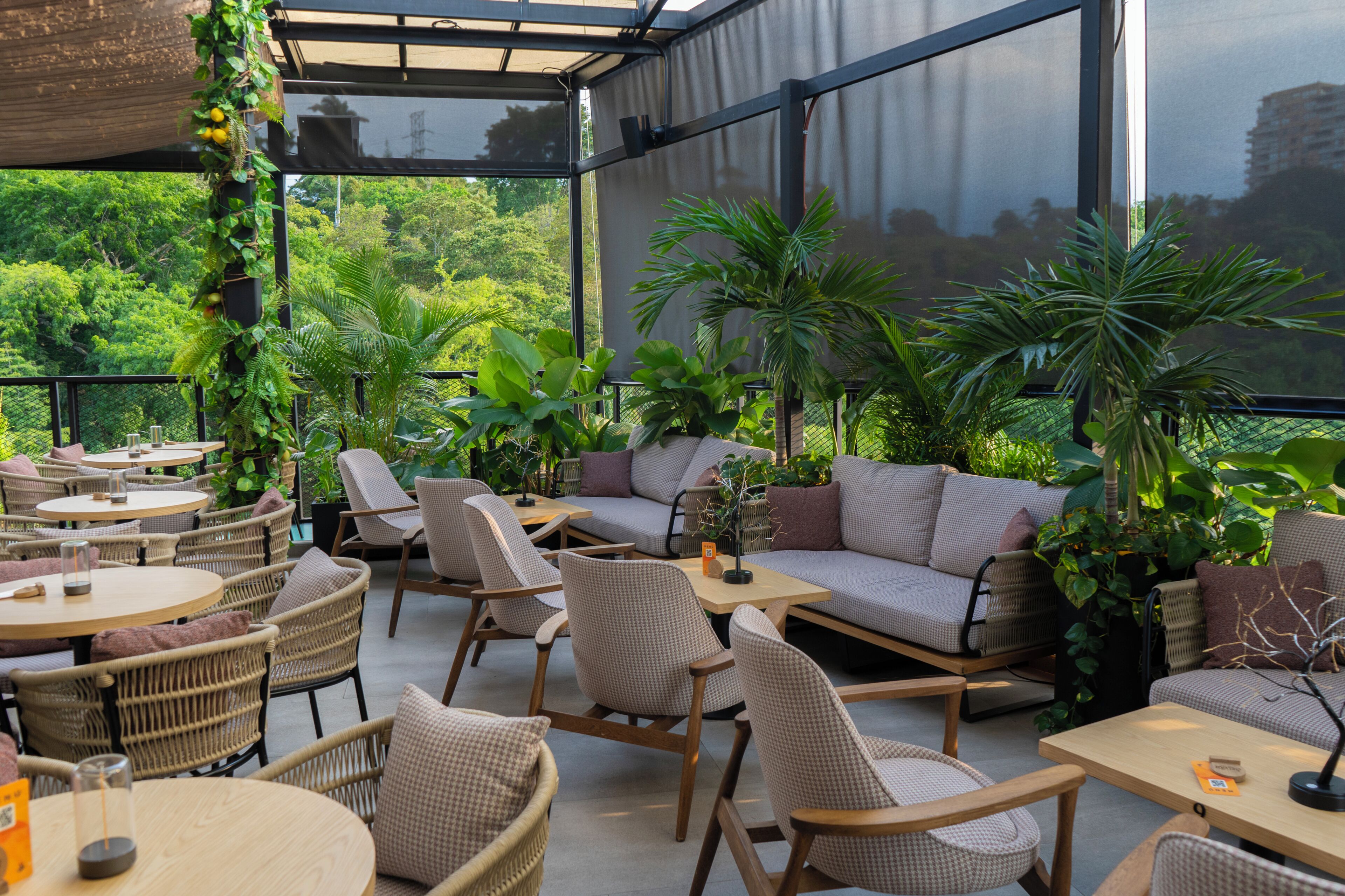 An outdoor seating area with wicker furniture, cushioned sofas, and potted plants.