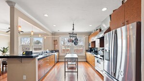 A spacious kitchen with wooden cabinets, a stainless steel refrigerator, and a central island. - Downtown loft in the heart of Lodi. Great for large groups! (Lodi)