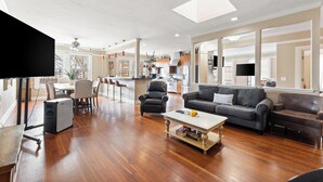 A spacious living room with a wooden floor, a grey sofa, a coffee table, and a TV on a stand. - Downtown loft in the heart of Lodi. Great for large groups! (Lodi)