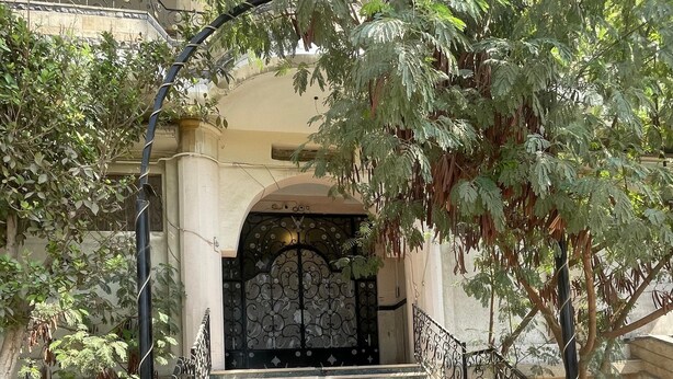 A set of stone steps leading to a gated entrance with a wrought iron railing, surrounded by trees and a building facade. - Narmar Hotel (Giza)