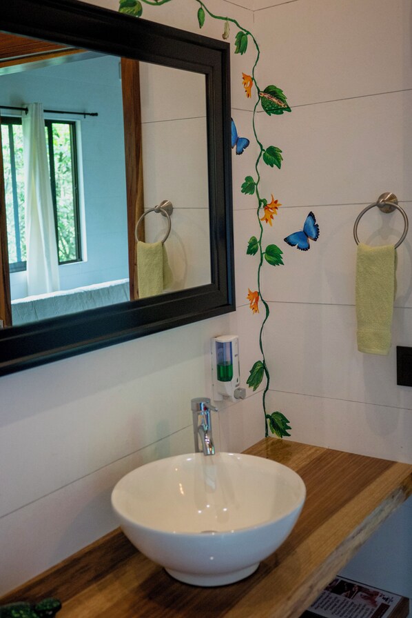 Un baño con lavamanos blanco, encimera de madera y espejo con marco negro.