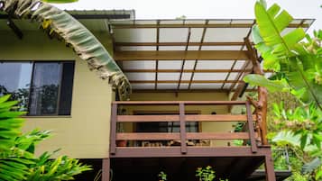 A two-story house with a wooden balcony and a thatched roof.