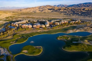 Vista aérea de un complejo turístico con varias edificaciones, un campo de golf y un lago grande.