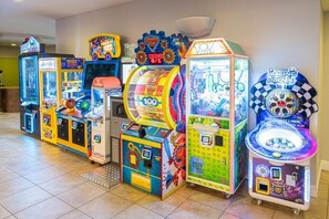 A row of brightly lit arcade machines in a room with tiled flooring. - Indio | Mobility-Friendly Resort Stay | Desert Sun & Pools | Accessible Studio (Indio)