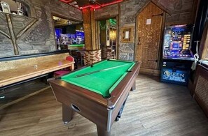 A pool table in a room with stone walls and a bar area.