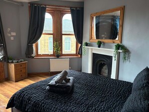 A bedroom with a bed, a window with curtains, a fireplace, and a mirror on the wall. - THE BULL ON THE BRIDGE (Sowerby Bridge)