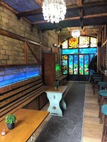 A cozy interior with wooden benches, a chandelier, and a stained glass window.